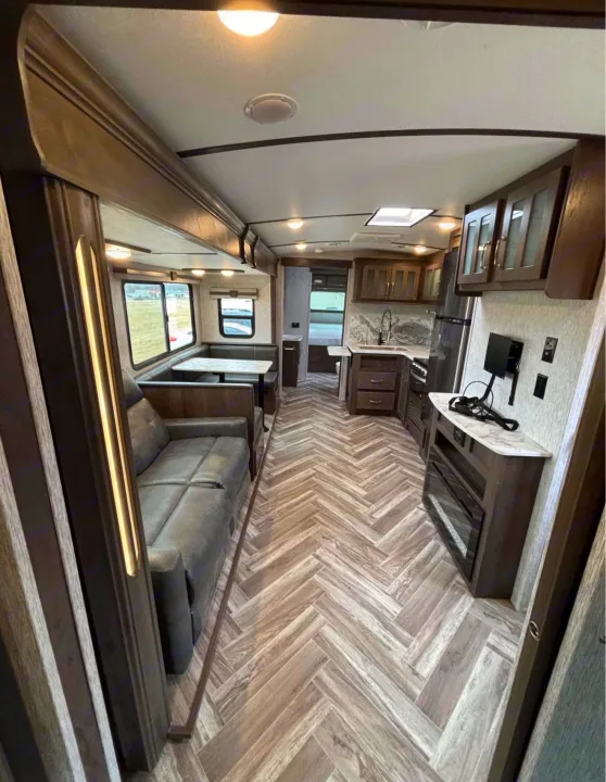 Spacious RV rental interior with living area, kitchen, dinette, fireplace, and stylish herringbone flooring.. Astoria Astoria Trailer 2022