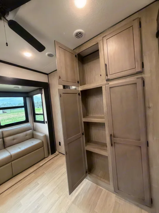 RV rental interior featuring ample light-toned cabinet and shelf storage, comfy sofa, and wood-look flooring. Ready for your adventures!. Durango Durango Fifth Wheel 2023
