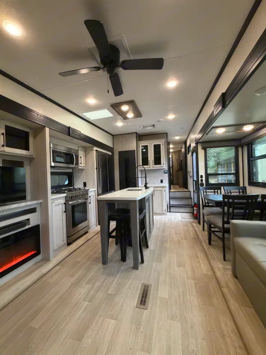 Inside a stylish RV rental: light wood floors, full kitchen with island, dining table, and fireplace for cozy comfort.. Durango Durango Fifth Wheel 2023