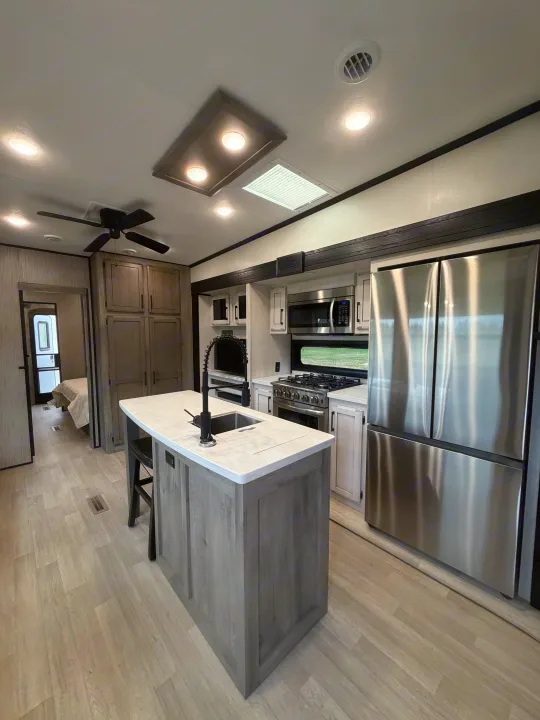 Spacious, modern RV rental kitchen with a central island, stainless steel appliances, and light wood-look flooring.. Durango Durango Fifth Wheel 2023