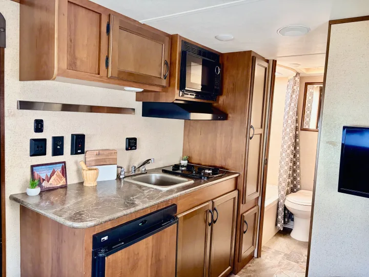 This RV rental offers a compact kitchen with all essentials: sink, stove, microwave, and fridge, plus an adjacent bathroom.. Jayco Jay Flight SLX 2015