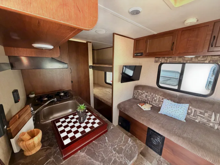 Cozy rv rental interior featuring a well-equipped kitchen, dinette with TV, and bunk beds. Perfect for travelers!. Jayco Jay Flight SLX 2015
