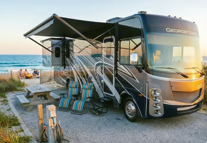 Experience beachside rv rental camping: A Georgetown motorhome is parked on a sandy site by the ocean, with a family by a campfire.. Forest River gt5 2022