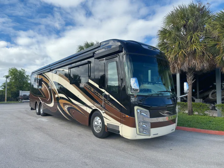 Luxury rv rental: A sleek black & brown motorhome with ornate side graphics, parked outdoors under a cloudy sky.. Entegra Coach Anthem 2019