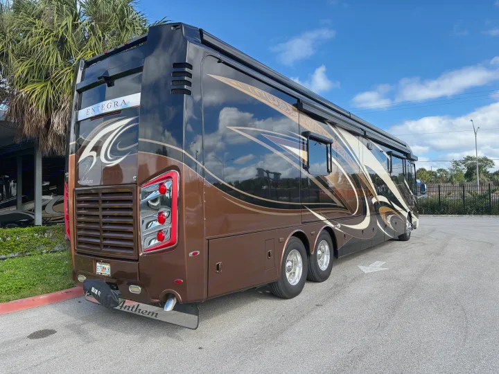 A brown and black Entegra Anthem luxury motorhome with gold and cream swirling patterns, ready for rv rental, parked on asphalt.. Entegra Coach Anthem 2019