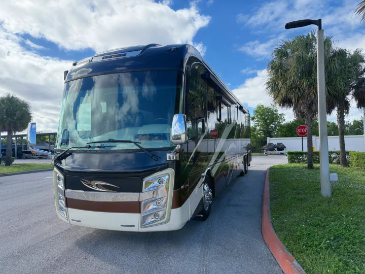 Stunning Entegra motorhome RV rental, black/brown, parked with palm trees and boats under blue sky.. Entegra Coach Anthem 2019