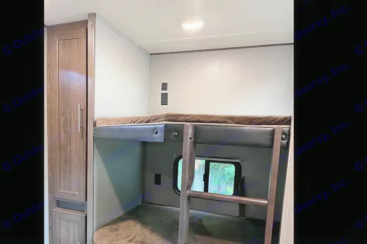 Inside an RV rental: cozy bunk beds with a ladder, window, and storage cabinet, featuring power outlets.. Crossroads RV zinger 2019