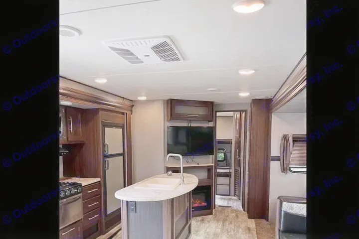 Explore this modern rv rental interior featuring a full kitchen, island sink, TV, and cozy fireplace. Ideal for road trips.. Crossroads RV zinger 2019