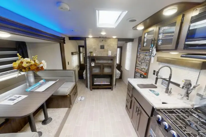 Bright rv rental interior featuring a dinette, kitchen with stove, and a central living area with an electric fireplace.. Forest River Cherokee Grey Wolf 2020