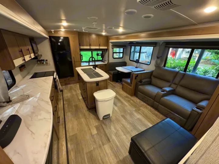 This comfy, modern RV rental features a full kitchen, island, dining booth, and recliners for a great travel experience.. Grand Design Imagine 2023