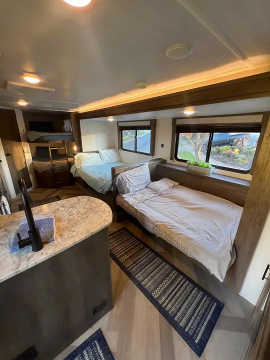 Cozy rv rental interior with bunk beds, multiple sleeping areas, and a kitchen counter. Ideal for family travel.. Forest River Wildwood X-Lite 2020