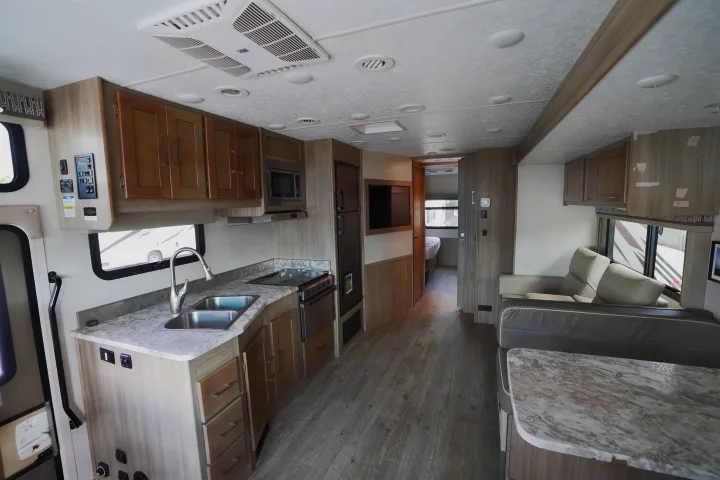Spacious rv rental interior featuring a modern kitchen, living area, and hallway to the bedroom.. Coachmen Pursuit 2019