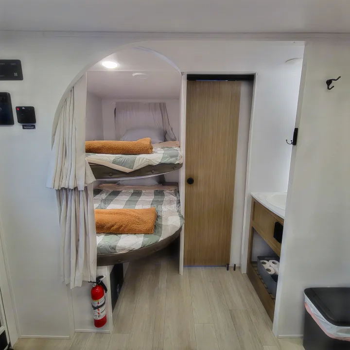 Inside an RV rental: a compact sleeping area with bunk beds, an adjacent small bathroom sink, and control panel on the wall.. Forest River Salem Cruise-Lite 2026
