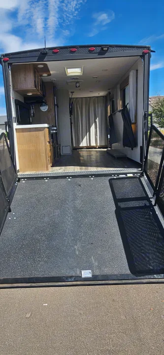 RV rental toy hauler with open ramp door, revealing a spacious interior, kitchen, and living area for your next trip.. Forest River Cherokee Grey Wolf 2023