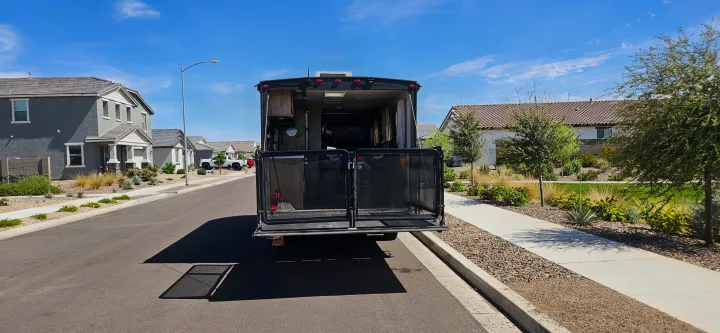 RV rental parked on a sunny street with its back ramp down, showcasing its interior cargo area within a residential neighborhood.. Forest River Cherokee Grey Wolf 2023