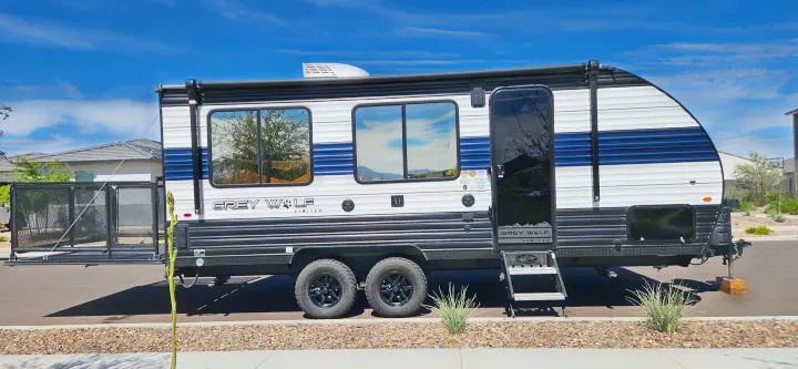 Grey Wolf travel trailer (RV rental) parked outdoors with a deployed rear ramp and main entry steps.. Forest River Cherokee Grey Wolf 2023