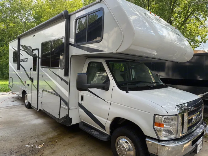 A large white Gulf Stream Conquest RV, potentially an rv rental, is parked outdoors with visible water droplets on its surface.. Conquest 6280 2024