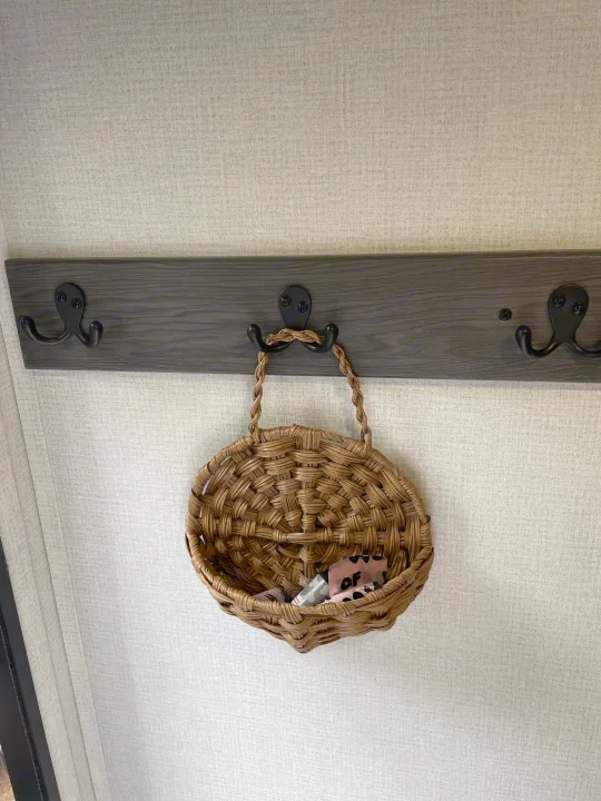 RV rental: A woven basket hangs on a dark gray coat rack against a light textured wall, holding small items.. Grand Design Transcend Xplor 2026