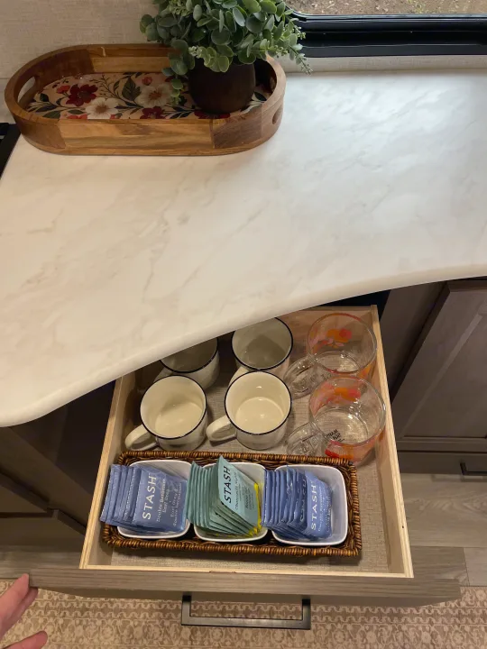 This RV rental features a convenient tea station with an organized drawer of Stash teas, mugs, and glassware, all ready for guests.. Grand Design Transcend Xplor 2026