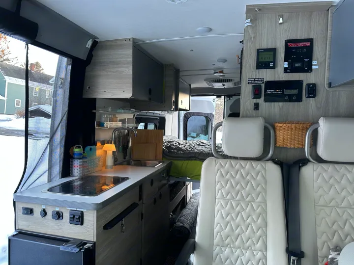 View inside a modern rv rental, showing a Winnebago camper van's compact kitchenette, control panel, and cozy living space.. Winnebago Solis 2022