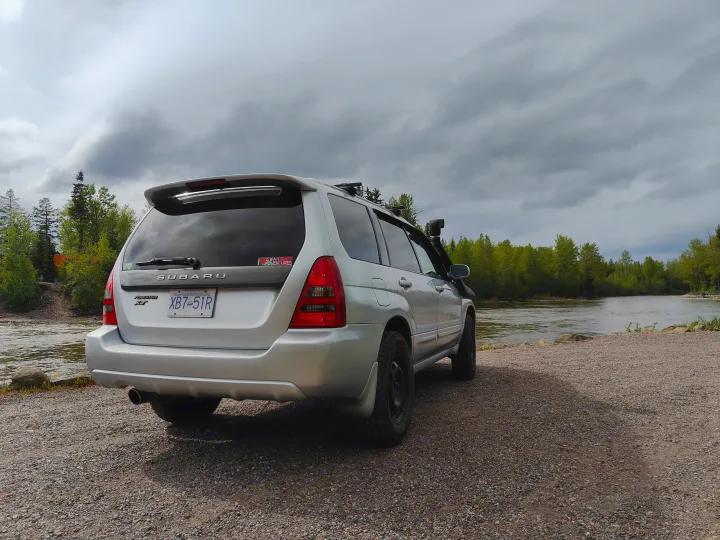 Silver Subaru Forester SUV by a river, perfect for outdoor adventures. An RV rental alternative for exploring British Columbia.. Subaru Forester 2007