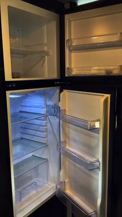 Empty RV rental refrigerator and freezer, with clear shelves and door bins, ready for your travel provisions.. Keystone RV Springdale 2023