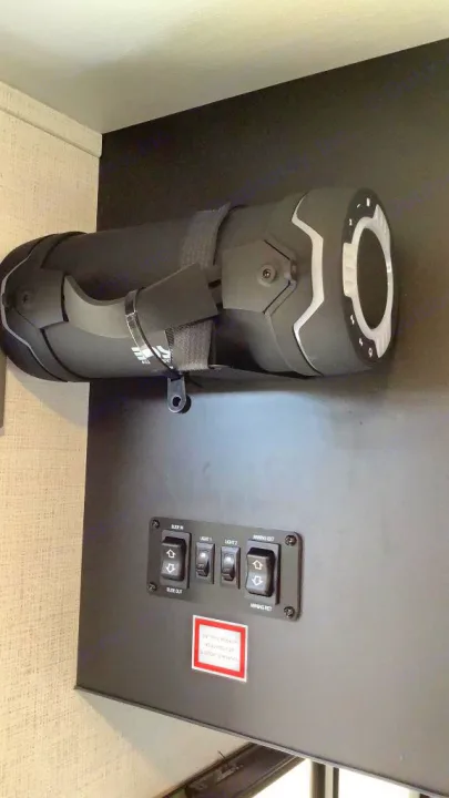 RV rental control panel: slide-out, awning, lights. A rugged mounted portable speaker is above it, inside the RV.. Keystone RV Springdale 2023