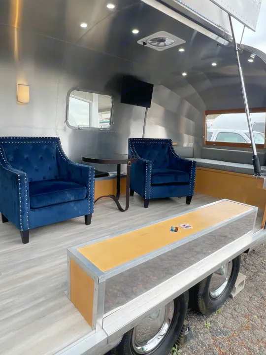 Step inside this stylish rv rental: an Airstream interior with two plush blue velvet armchairs, a built-in bench, and modern lighting.. Airstream Airstream 1971