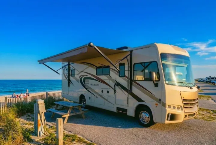 RV rental: Class A motorhome on a sunny beach campsite with an awning, picnic table, and ocean views.. Forest River Georgetown 2018