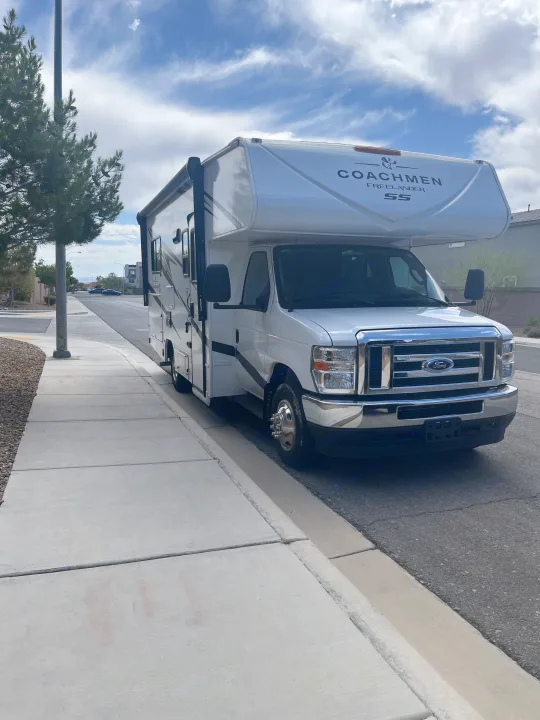 A white Coachmen Freelander SS RV rental is parked curbside under a partly cloudy sky, ready for a road trip.. Freelander 21QSS 2025