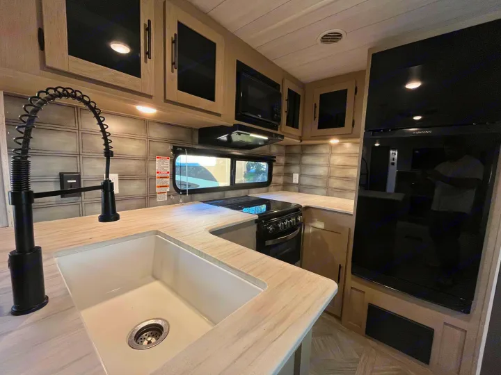 Spacious, modern RV rental kitchen with sleek black appliances, a large sink, and wrap-around counters.. Forest River Salem 2023