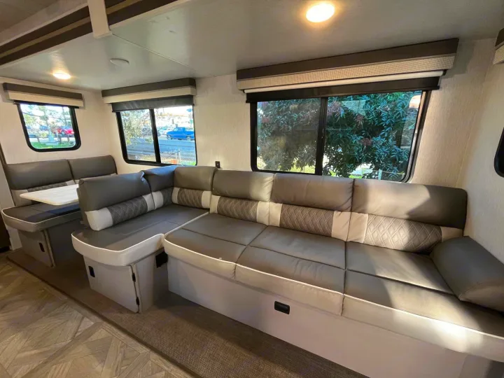 Spacious RV rental living area featuring a comfortable L-shaped sofa, dinette, large windows, and modern interior design.. Forest River Salem 2023