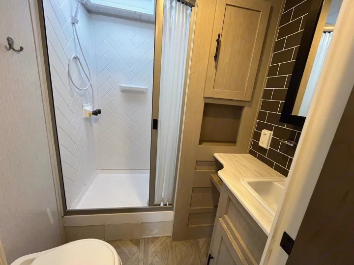 Compact RV rental bathroom: shower, vanity with sink, mirror, and partially visible toilet.. Forest River Salem 2023