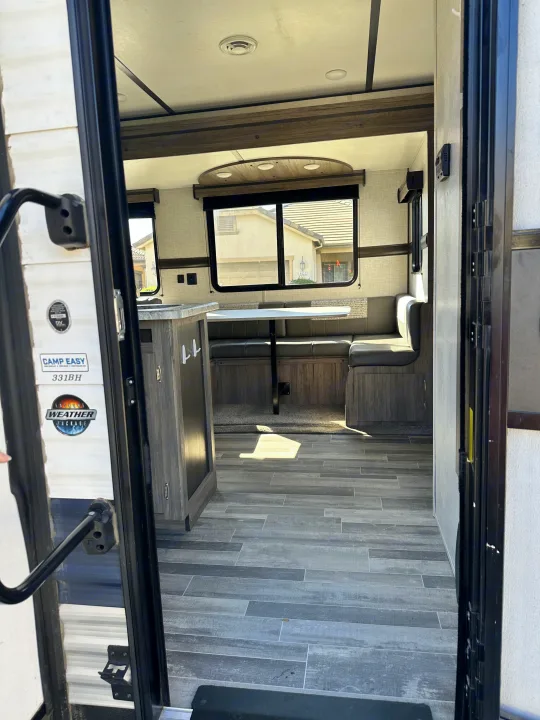 RV rental interior: View from the entry door of a modern camper with a dinette, kitchen counter, and grey wood-look flooring.. Crossroads RV Zinger 2021