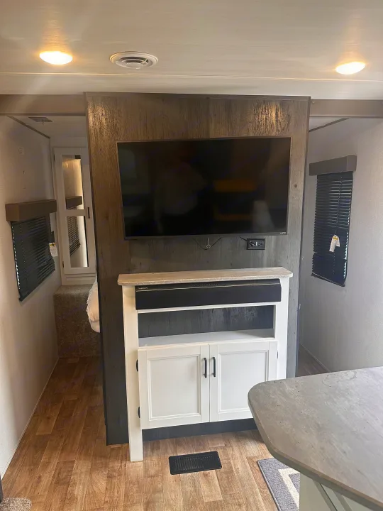 Inside an RV rental: sleek entertainment center with TV, soundbar, and white cabinet, creating a stylish mobile living space.. Keystone RV Hideout 2022