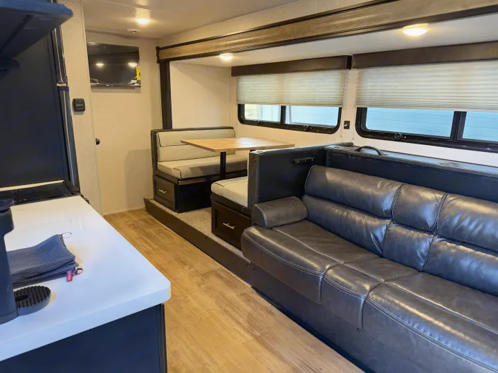 Modern RV rental interior: a bright kitchen counter, elevated dining booth, and comfortable sofa, creating a cozy living space.. Forest River Cherokee Wolf Pup Black Label 2021