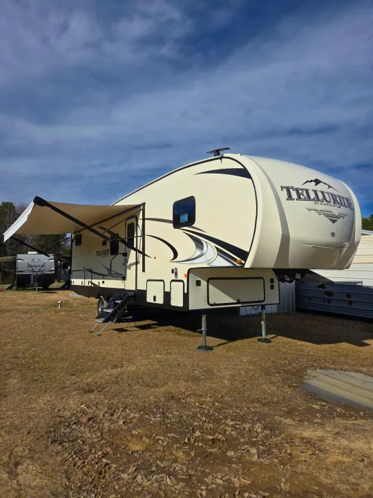 This cream Starcraft Telluride fifth-wheel RV rental is ready for your adventure. Awning extended, parked on dry ground.. Starcraft Telluride 2021