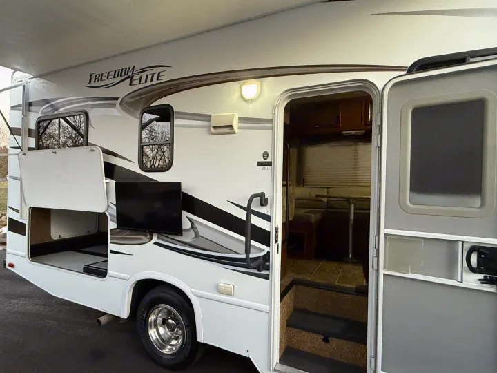 Explore this Freedom Elite RV rental with its inviting open door, cozy interior, outdoor TV, and spacious storage.. Thor Freedom Elite 2012