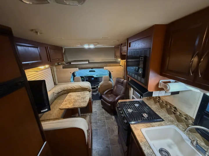 Spacious rv rental interior featuring a kitchen, dinette, cozy living area, and cab-over bed.. Thor Freedom Elite 2012