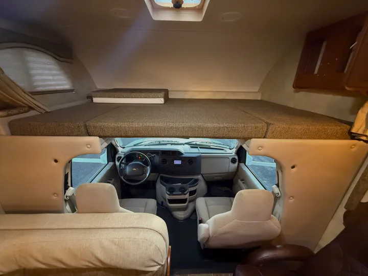 RV rental interior: A cozy cab-over bunk bed overlooks the driver's cockpit and front passenger seats.. Thor Freedom Elite 2012