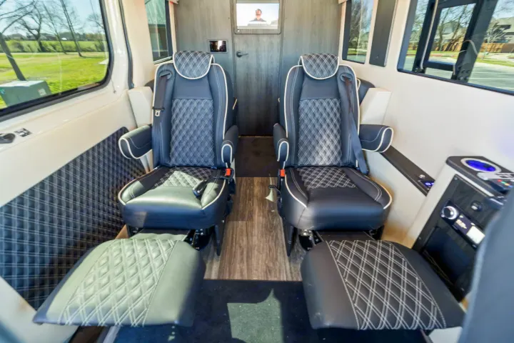 Inside a luxurious RV rental: two plush black captain's chairs with diamond stitching, individual footrests, and modern controls.. OGV Luxury Coach V-Cruise 2026