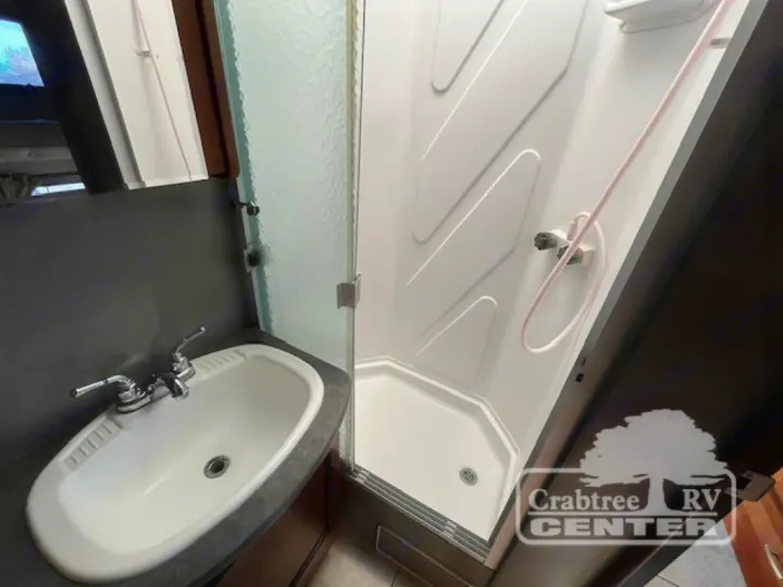 This RV rental's clean bathroom features a white sink, dark vanity, and a bright, clear-doored shower stall.. Holiday Rambler Admiral 2017