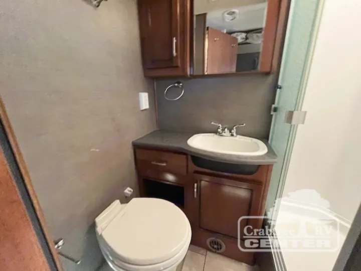 Compact RV rental bathroom interior featuring a toilet, vanity with sink, and shower, offering all necessary amenities.. Holiday Rambler Admiral 2017