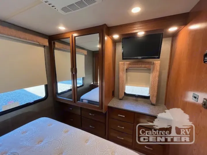 Cozy RV rental bedroom with a comfy bed, mirrored wardrobe, windows, TV, and ample storage. Ideal for comfortable travels.. Holiday Rambler Admiral 2017