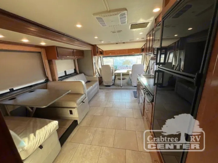 Spacious RV rental interior shows a dinette, sofa, kitchen, and refrigerator. Light tile floor and wood cabinets.. Holiday Rambler Admiral 2017