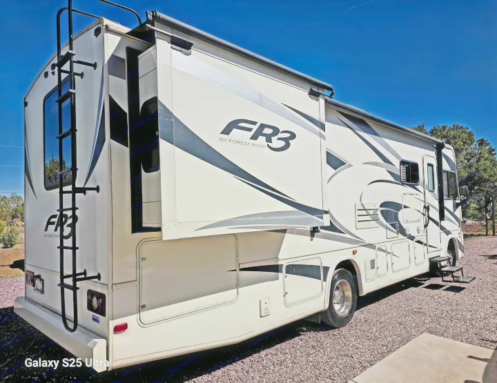 A sleek FR3 by Forest River motorhome (RV rental) with its slide-out extended, parked on gravel under a clear blue sky, ideal for travel.. Forest River FR3 30DS 2017