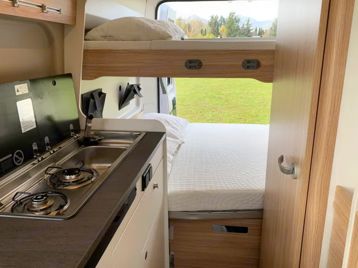 Cozy rv rental interior with kitchen, bunk bed, lower bed, and a scenic window view of nature.. Sunlight Cliff 600 2023