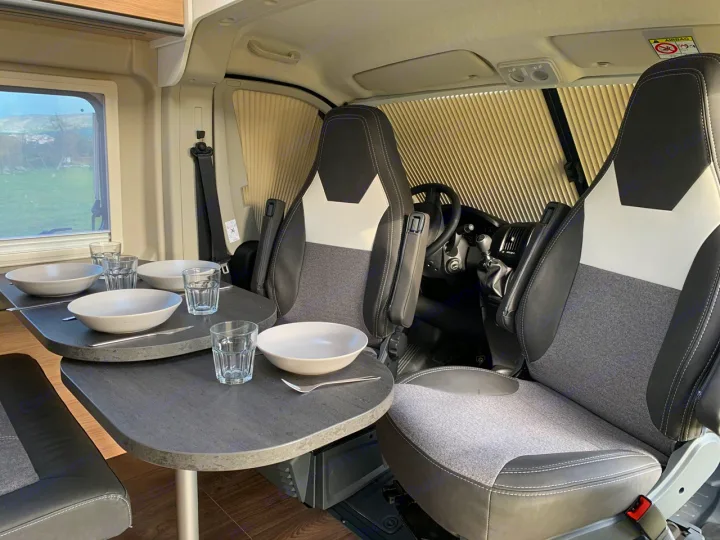 RV rental interior: cozy dining area with two tables, front swivel seats, and a scenic window view.. Sunlight Cliff 600 2023