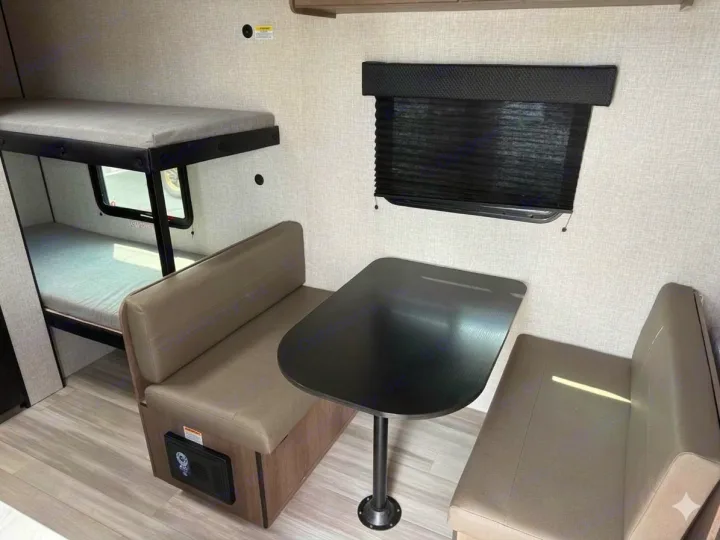 RV rental interior featuring bunk beds, a dinette with table & benches, and a window with a black blind.. Starcraft Autumn Ridge 2026