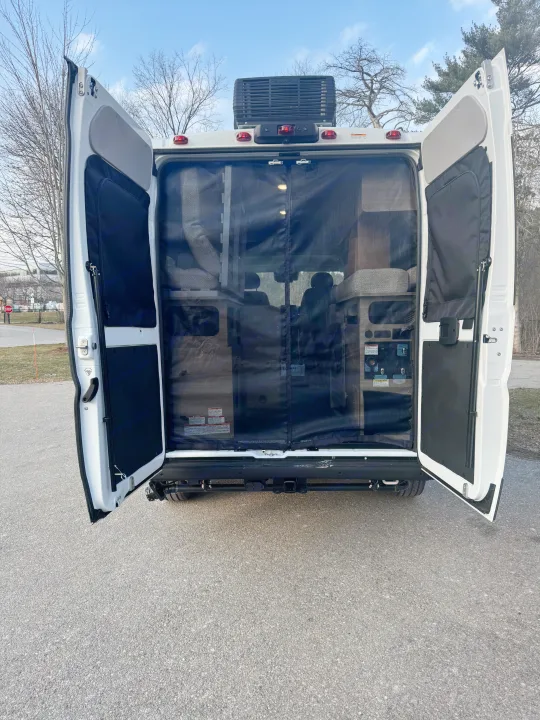This RV rental showcases its open rear doors with a mesh screen, offering a peek at the cozy interior for your next adventure.. Winnebago Solis 2025